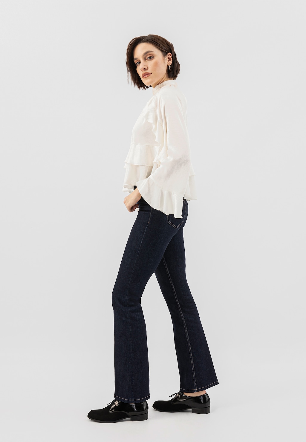 Osoba w białej bluzce i granatowych jeansach prezentująca czarne półbuty damskie Wojas model 46331-71 z łączonych skór, widoczne z boku.