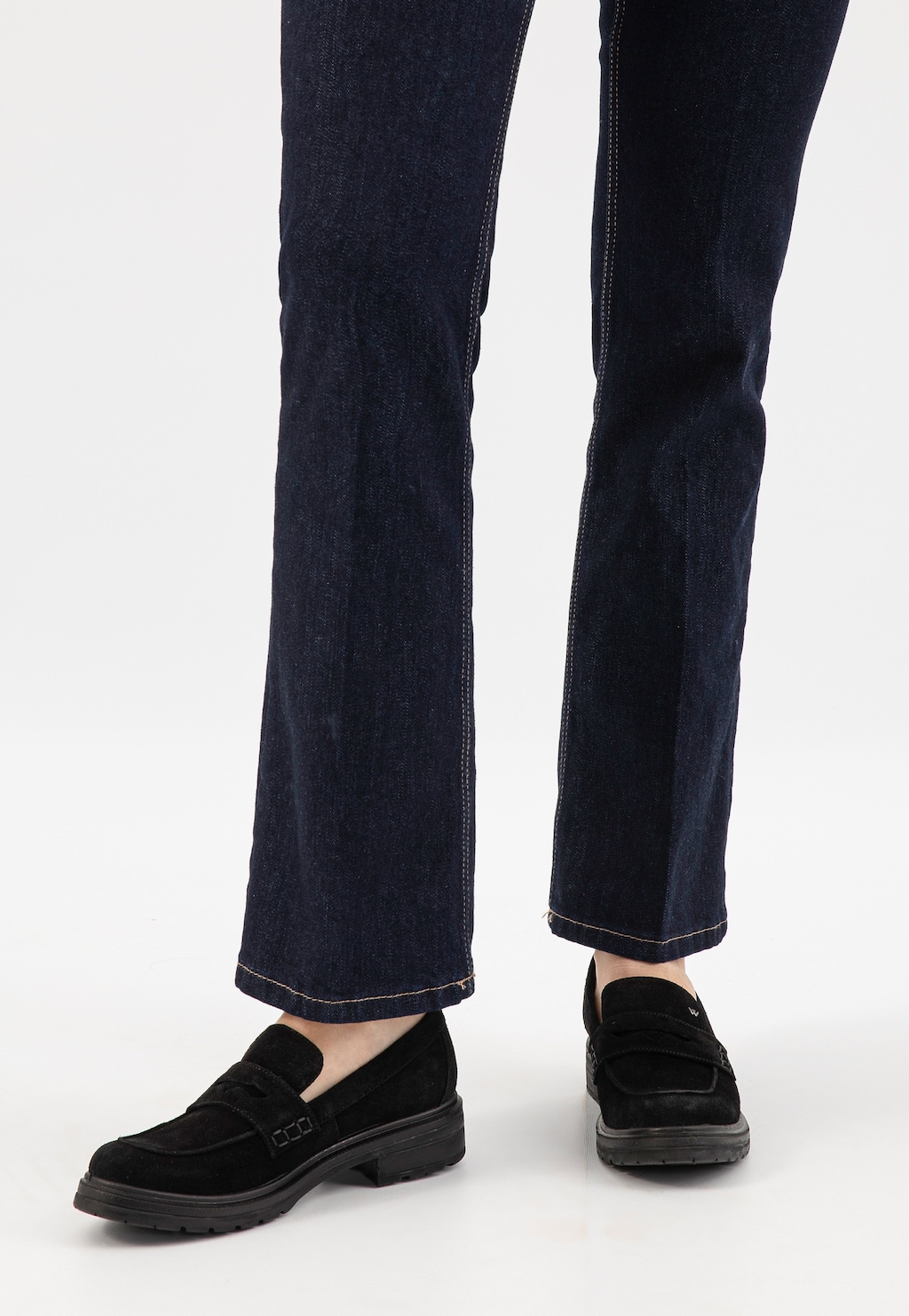 Czarne mokasyny damskie Wojas 46301-61 z dwoiny welurowej na grubej podeszwie, noszone z szerokimi granatowymi jeansami, widok z dołu na stopy.