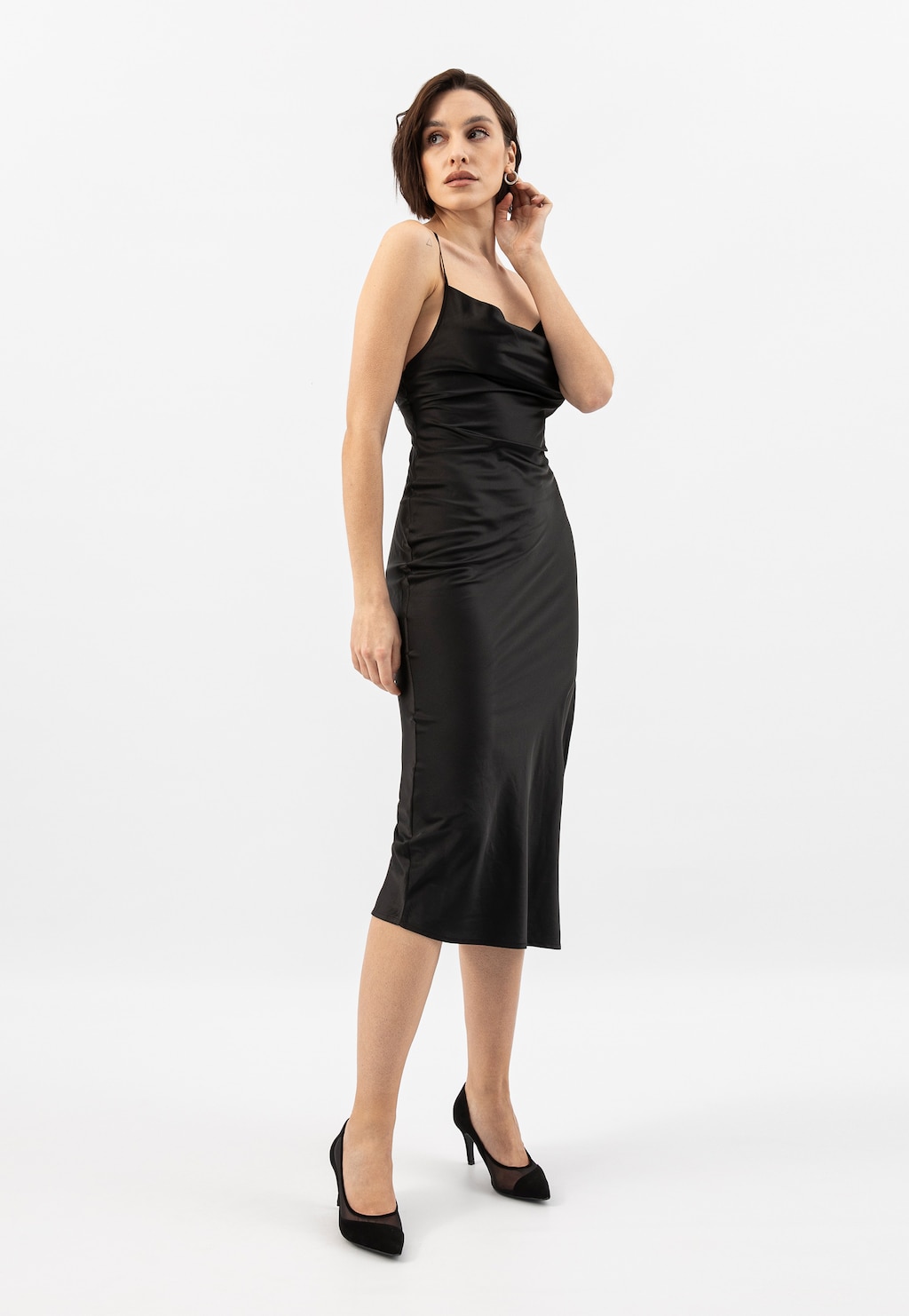 Elegancka modelka w czarnej sukience na ramiączkach, prezentująca czarne czółenka Wojas z noskiem w szpic z siateczką, model 35156-81.