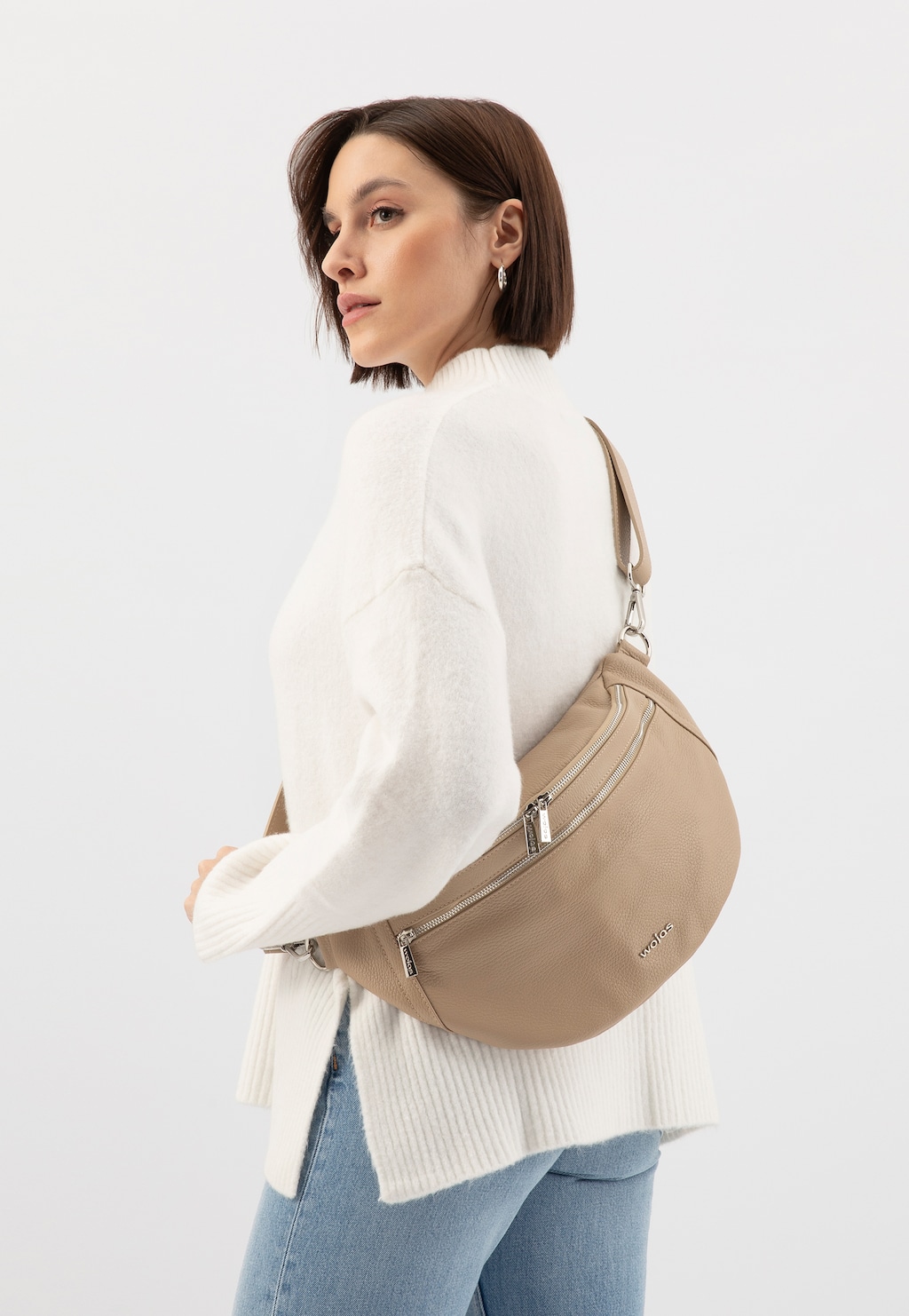Skórzana beżowa torebka nerka Wojas model 80298-54 prezentowana na osobie w białym swetrze. Elegancka nerka z kieszeniami na zamek błyskawiczny, noszona przez ramię.