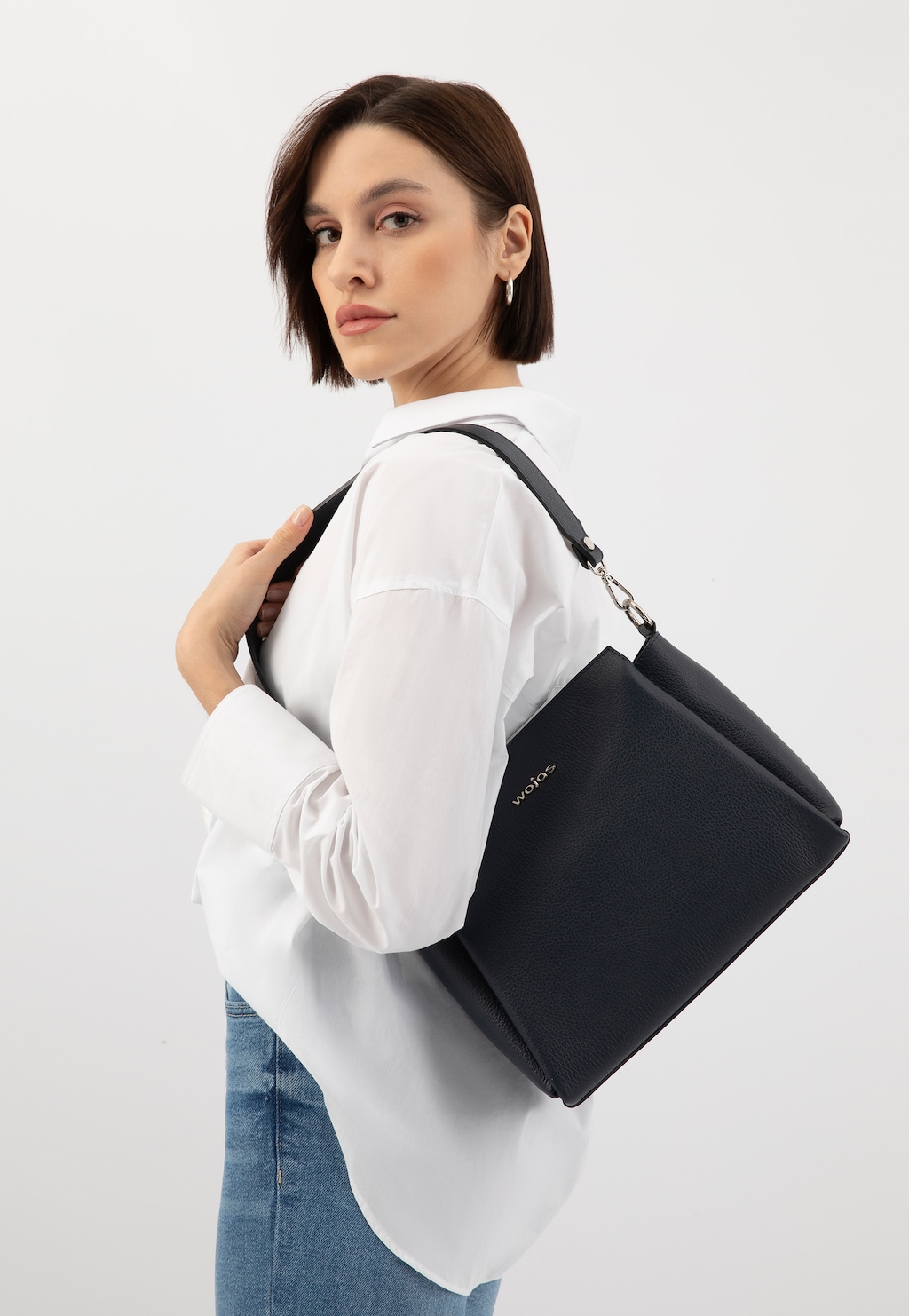 Granatowa torebka damska Wojas model 80106-56 na ramieniu modelki w białej koszuli i jeansach, elegancki dodatek na co dzień.