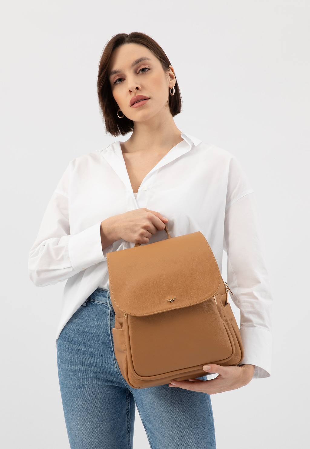 Elegancki beżowy skórzany plecak miejski Wojas 80082-54 z klapką, prezentowany w stylizacji z białą koszulą i jeansami, idealny do codziennych stylizacji.