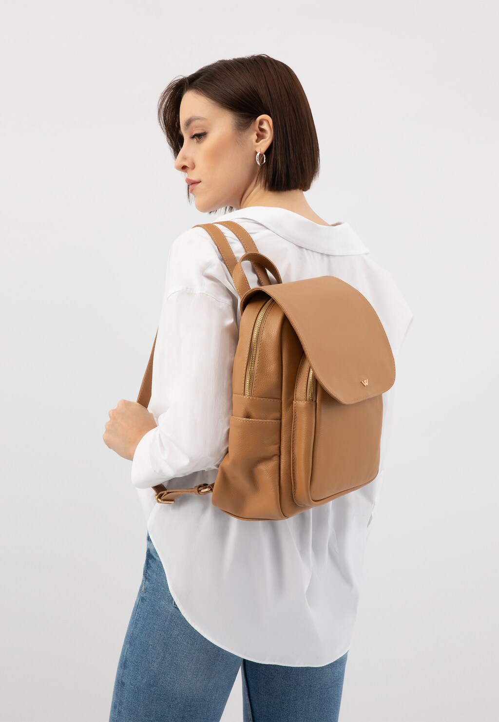 Beżowy skórzany plecak miejski Wojas model 80082-54 z charakterystyczną klapką, pokazany z profilu na osobie w białej koszuli i jeansach.