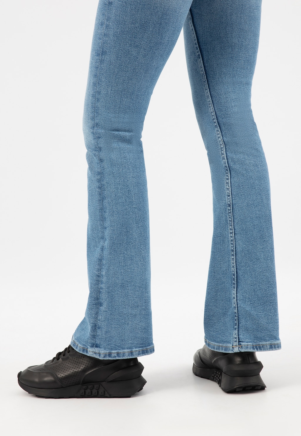 Czarne skórzane sneakersy damskie Wojas model 46306-51 prezentowane na nogach osoby w jasnych jeansach typu dzwony, widoczne z boku.