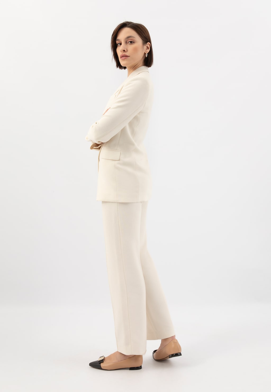 Elegancki kremowy garnitur damski uzupełniony beżowymi balerinami Wojas 46299-54 z czarnymi wstawkami. Modelka w klasycznej pozie ukazująca stylizację biznesową.