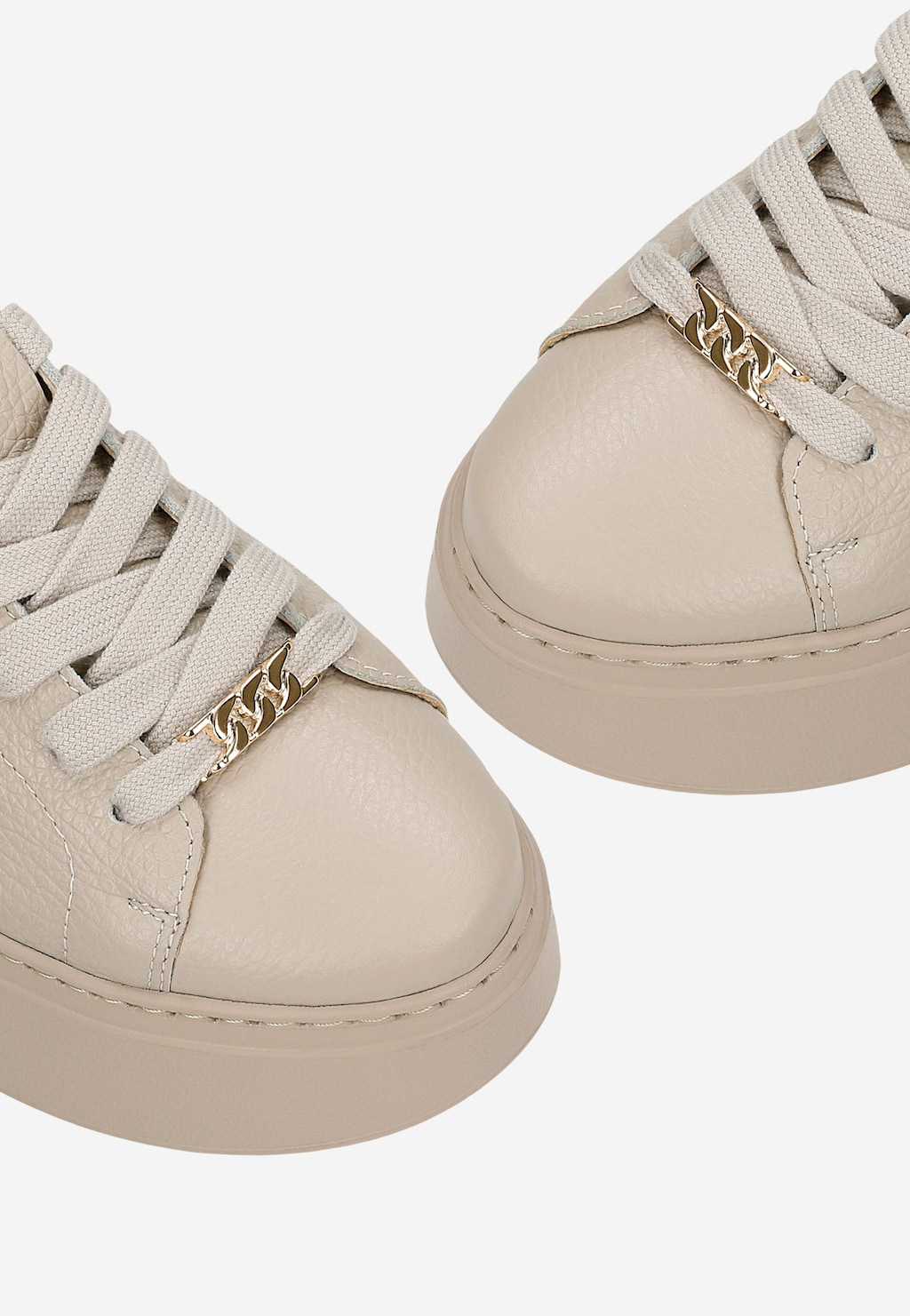 Beżowe trampki damskie Wojas 46285-54 na wysokiej podeszwie z ozdobnym złotym łańcuszkiem przy sznurówkach. Zbliżenie na przednią część butów ukazujące teksturę skóry.