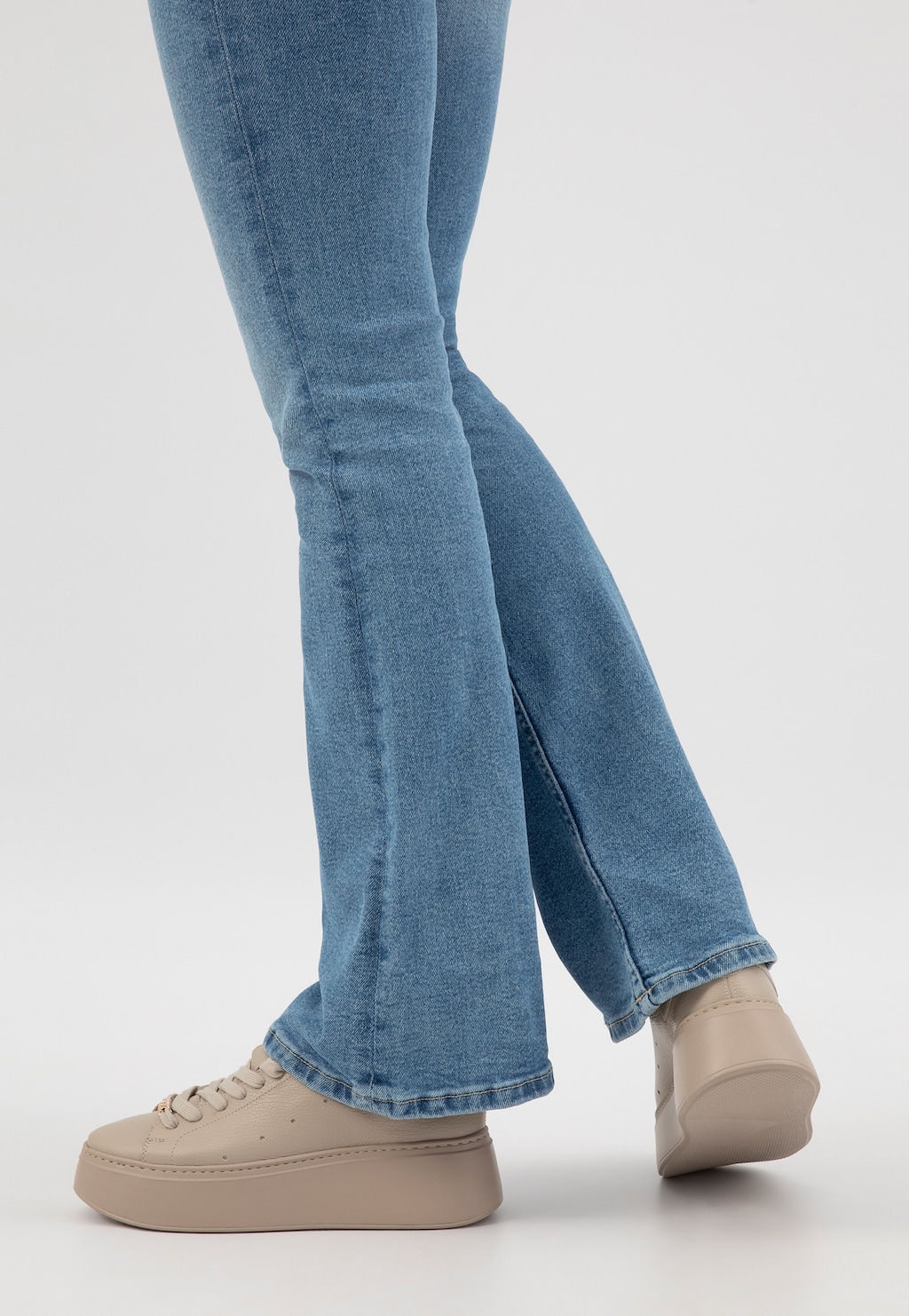 Beżowe trampki damskie Wojas 46285-54 na wysokiej podeszwie prezentowane na nogach w niebieskich jeansach, ukazujące stylowy wygląd z boku.