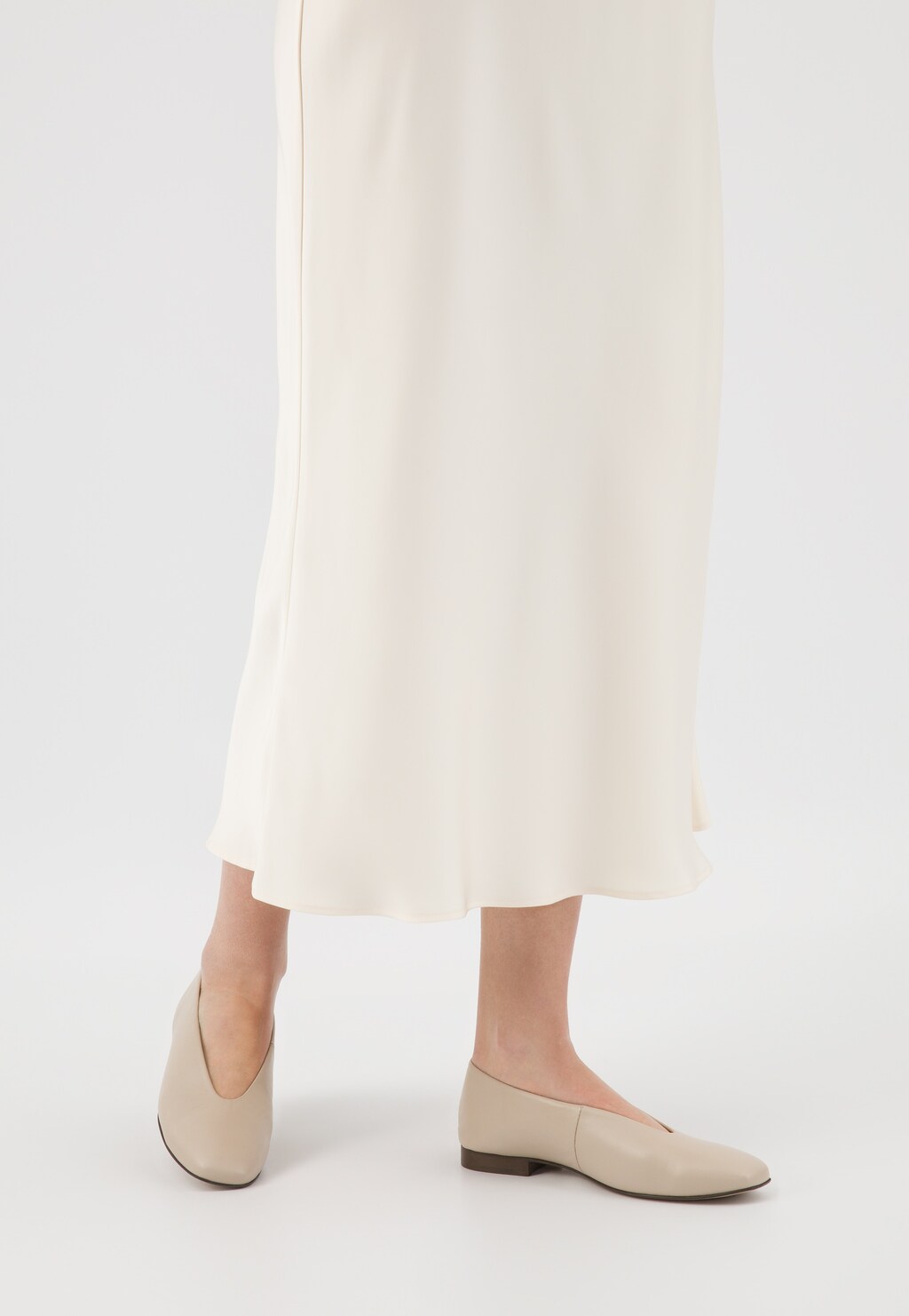 Beżowe baleriny Wojas ze skóry licowej model 44030-54 na nogach osoby w kremowej sukience, pokazane z perspektywy dolnej części ciała, podkreślające elegancki, minimalistyczny styl.