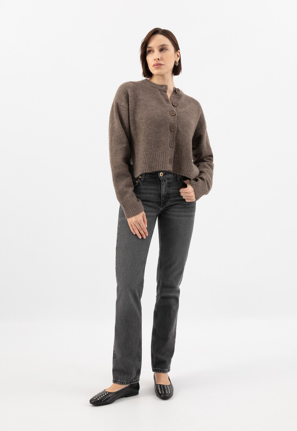 Czarne baleriny Wojas 44044-51 ze srebrnymi nitami na modelce ubranej w brązowy rozpinany sweter i szare jeansy. Stylizacja prezentuje obuwie z pełnej sylwetki.