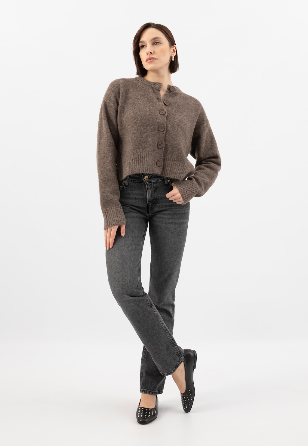 Modelka w szarym swetrze i jeansach prezentuje czarne baleriny Wojas model 44044-51 ze srebrnymi nitami, widoczne z przodu na stopach.