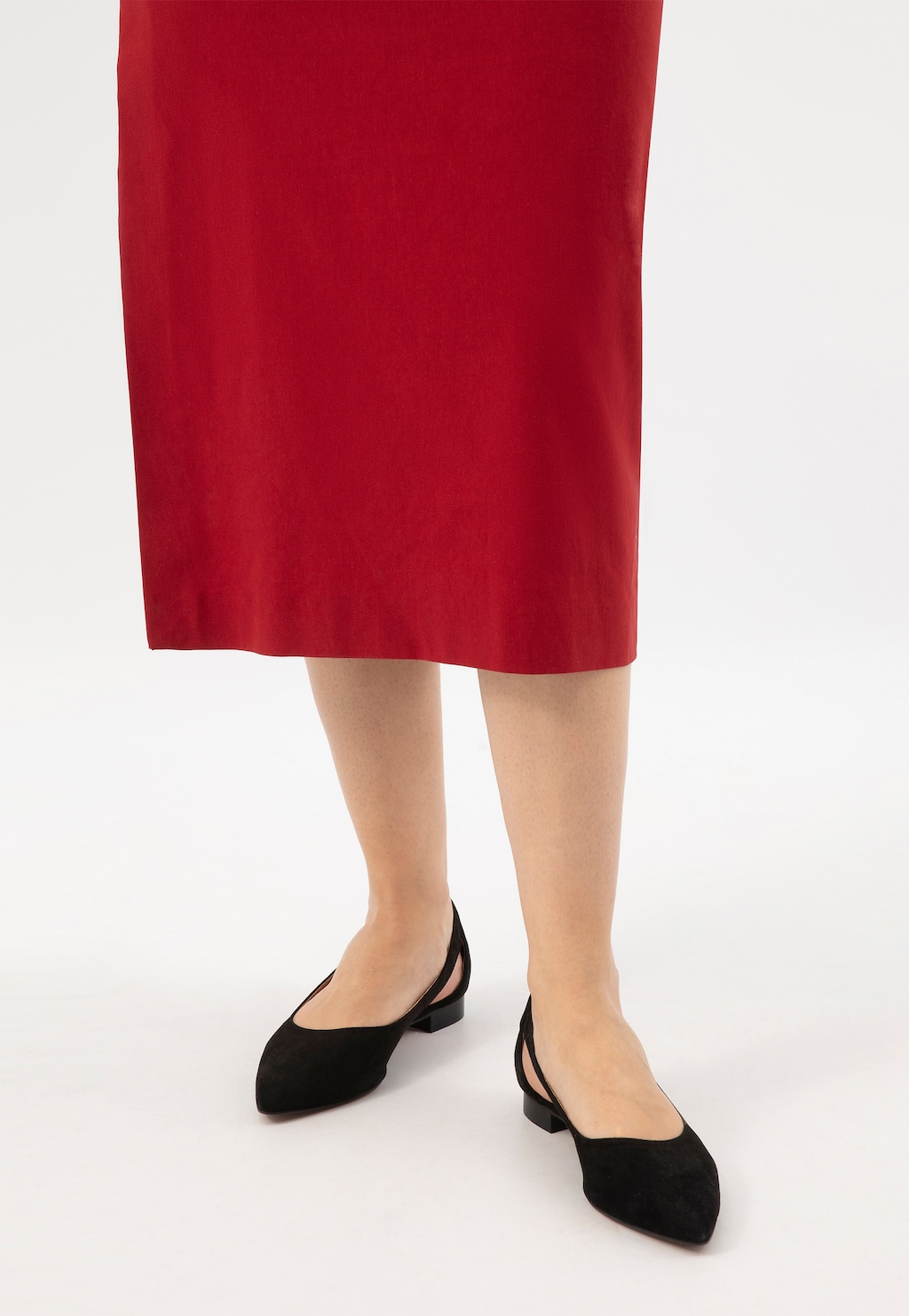 Eleganckie czarne czółenka Wojas model 44036-61 z noskiem w szpic i stylowymi wycięciami, prezentowane na nogach modelki w czerwonej spódnicy.