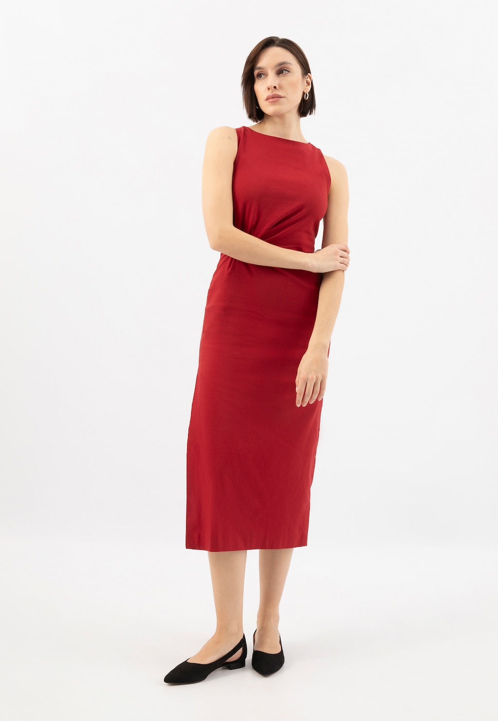 Modelka w czerwonej sukience midi prezentuje czarne czółenka Wojas 44036-61 z wycięciami i szpiczastym noskiem, idealne do eleganckich stylizacji.