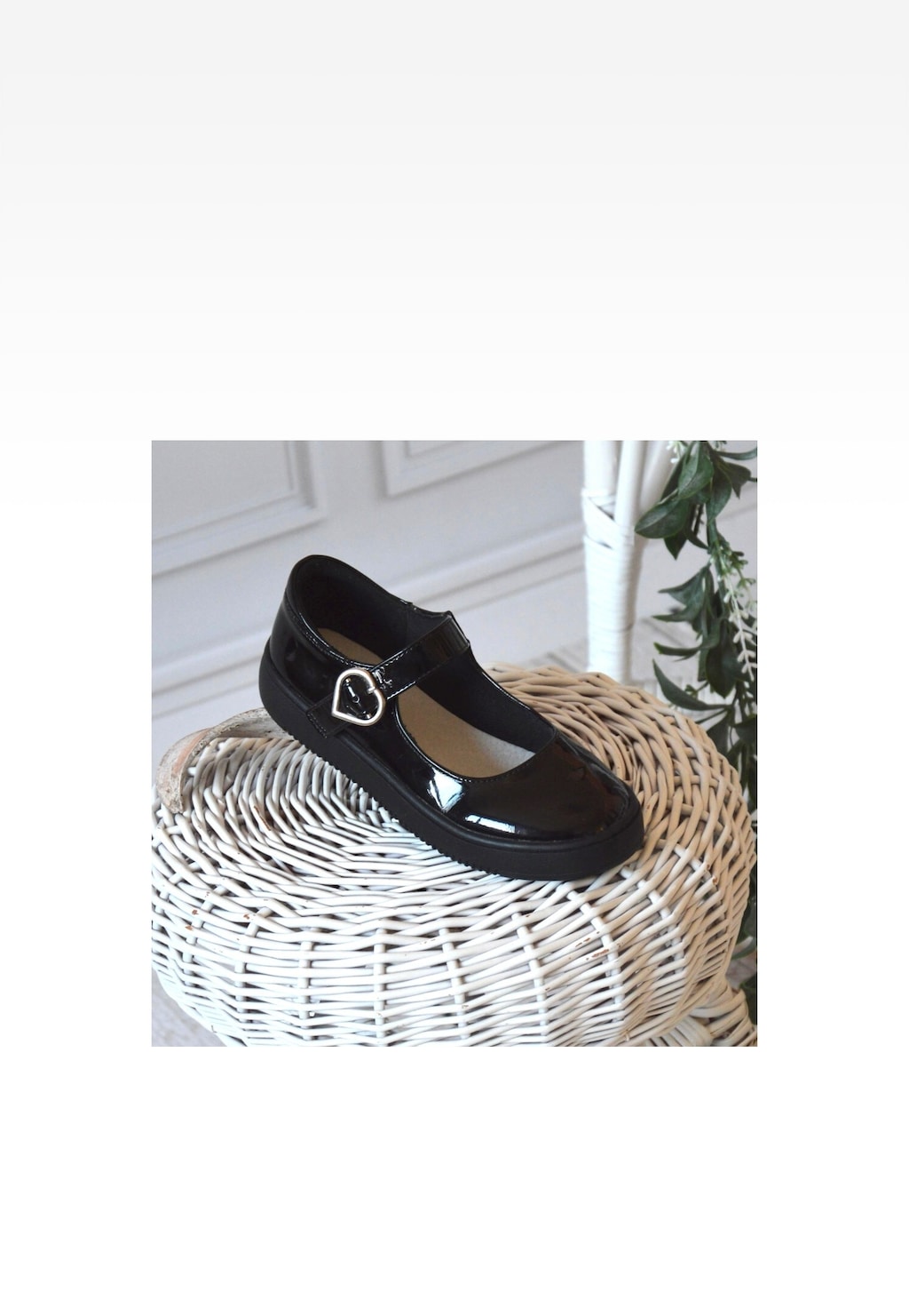 Czarne eleganckie baleriny dziewczęce Bartek 83006-31 z lakierowanej skóry, z paskiem i klamrą w kształcie serca, prezentowane na wiklinowym koszyku.