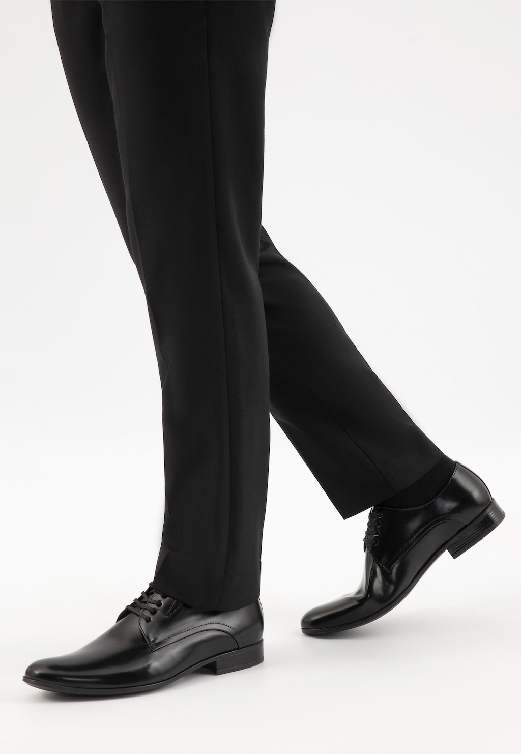 Eleganckie czarne półbuty męskie Wojas 9037-51 ze skóry licowej prezentowane na nogach w ciemnych spodniach. Widok z boku podkreśla klasyczny, biznesowy charakter obuwia.