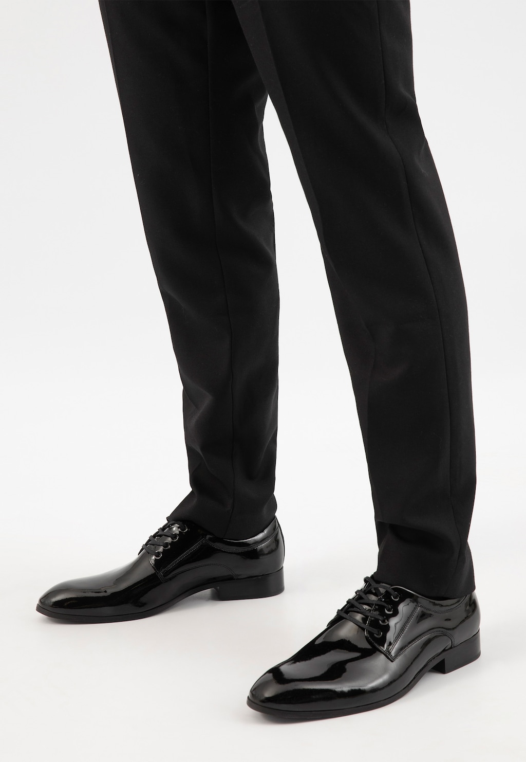 Czarne lakierowane męskie półbuty Wojas model 9005-31 w stylu formal, noszone z eleganckimi spodniami garniturowymi, widok z perspektywy dolnej części nóg.