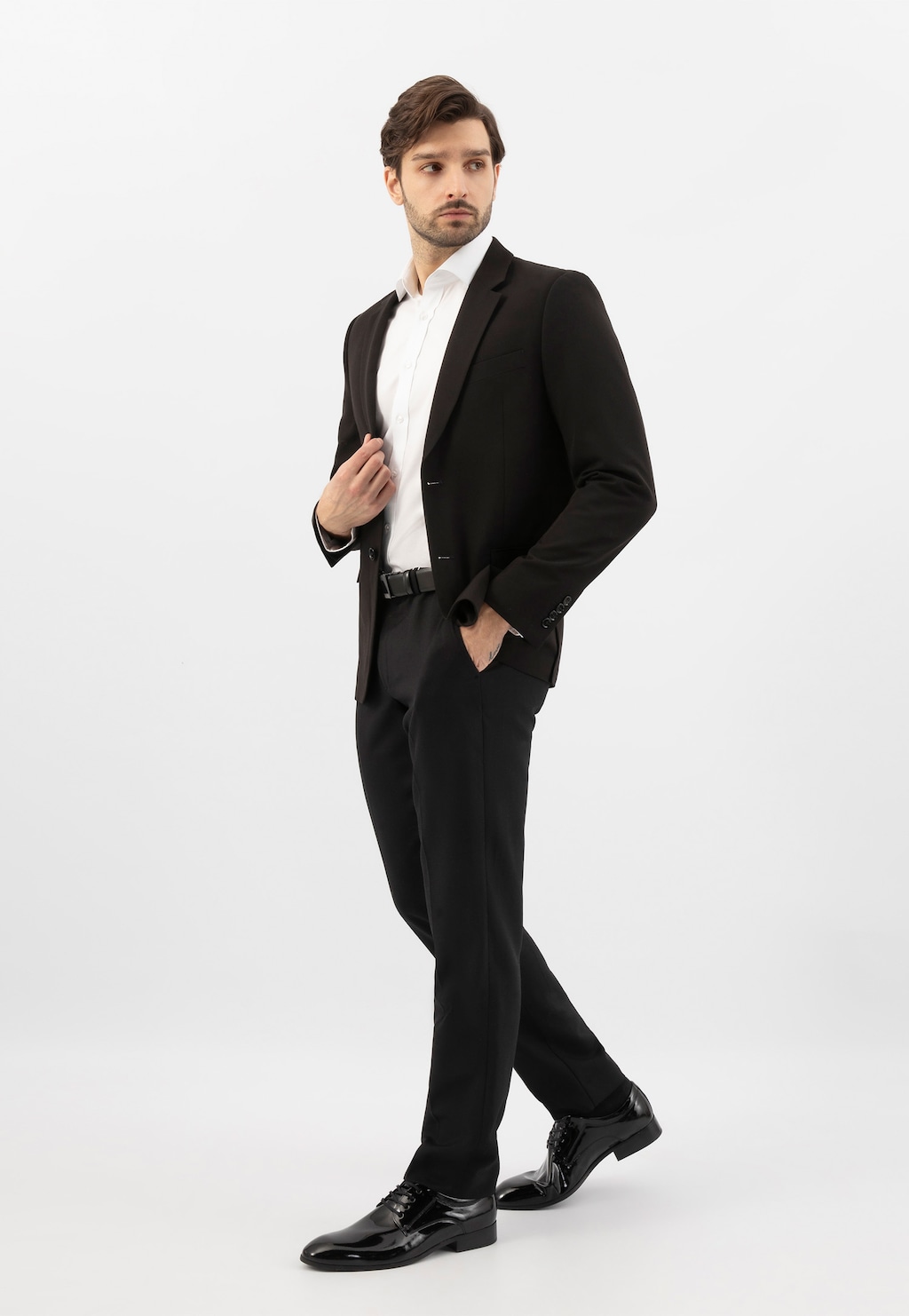 Model w eleganckim czarnym garniturze prezentuje czarne lakierowane półbuty męskie Wojas 9005-31 w stylu formal, idealne do oficjalnych stylizacji biznesowych.