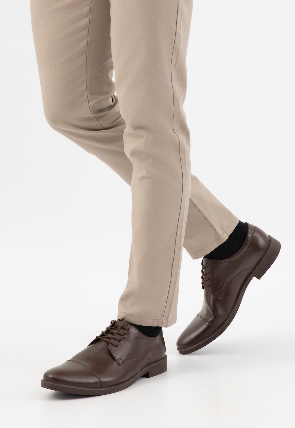 Eleganckie brązowe półbuty męskie Wojas 10073-52 ze skóry licowej zaprezentowane na nogach modela w jasnych spodniach. Widoczne sznurowanie i klasyczny fason obuwia.