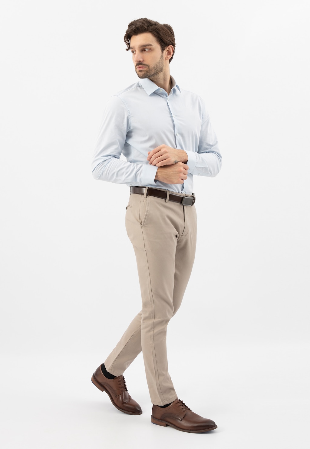 Mężczyzna w eleganckiej stylizacji z jasnoniebieską koszulą i beżowymi spodniami, prezentujący brązowe sznurowane półbuty Wojas model 10133-52 ze skóry licowej.