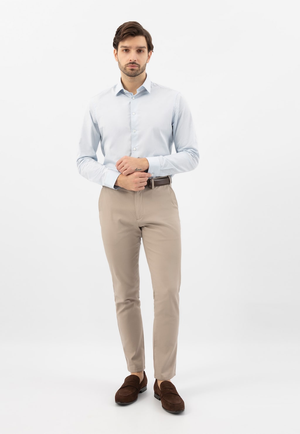 Model w eleganckiej stylizacji z brązowymi loafersami Wojas 10196-62 z dwoiny welurowej, jasnoniebieską koszulą i beżowymi spodniami.