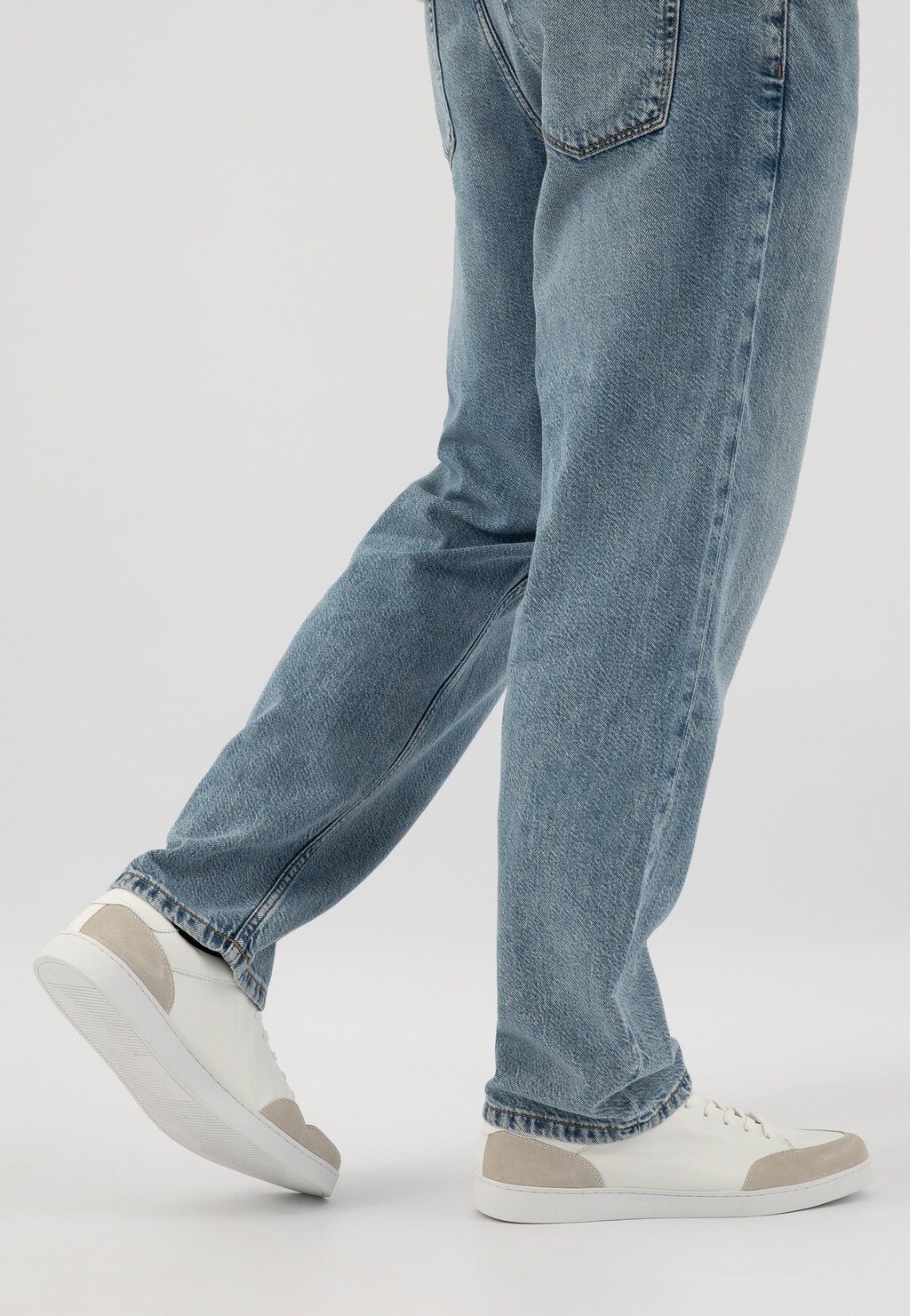 Białe trampki męskie Wojas model 10217-50 z szarymi wstawkami noszone do klasycznych jeansów w jasnym odcieniu, widok z boku pokazujący stylową sylwetkę obuwia.