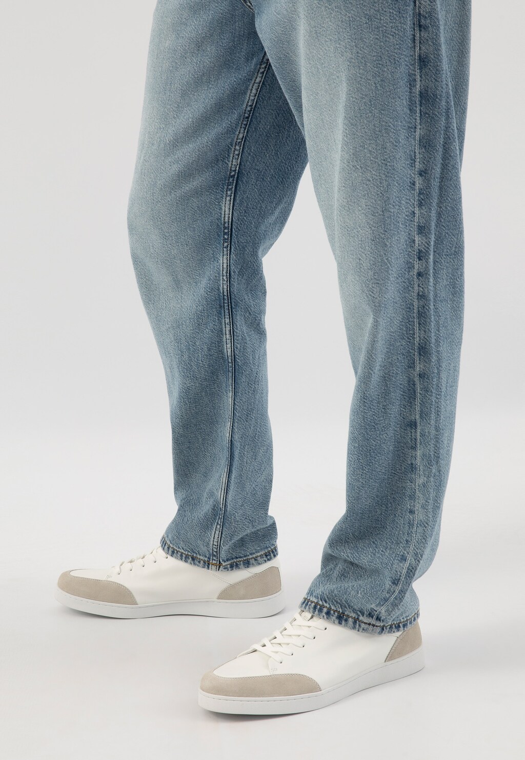 Białe trampki męskie Wojas model 10217-50 z szarymi wstawkami, prezentowane na nogach w jasnych jeansach, widok z boku podkreślający sportowy design obuwia.