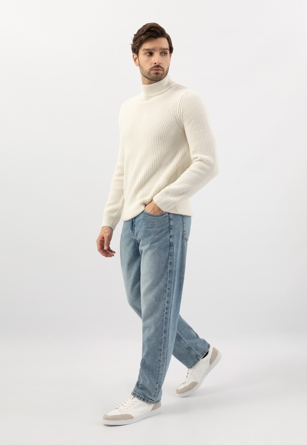 Stylizacja z białymi trampkami Wojas 10217-50 z szarymi wstawkami, noszonymi do jasnych jeansów i kremowego golfu. Buty widoczne podczas chodu.