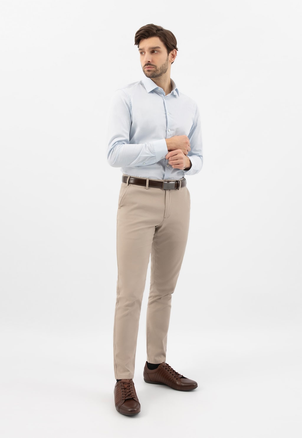 Model w eleganckiej stylizacji – jasna koszula, beżowe spodnie i brązowe skórzane sneakersy Wojas model 10240-52 z charakterystycznymi przeszyciami.