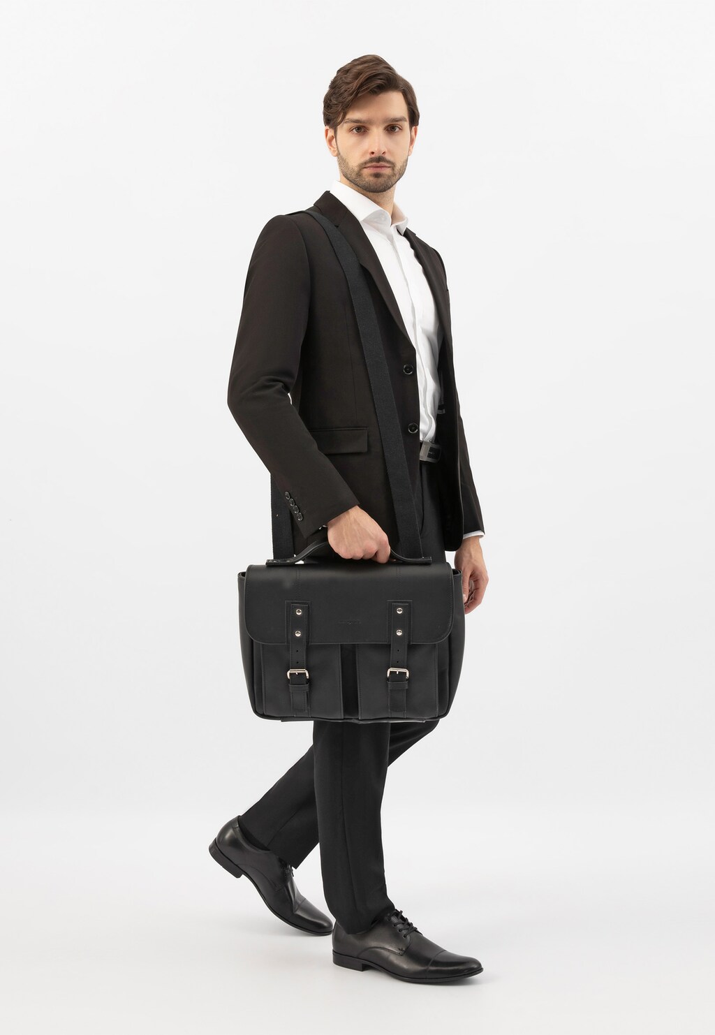 Model w eleganckim garniturze prezentujący czarną skórzaną torbę-plecak 2w1 Wojas model 80399-51, idealną do stylizacji biznesowych.