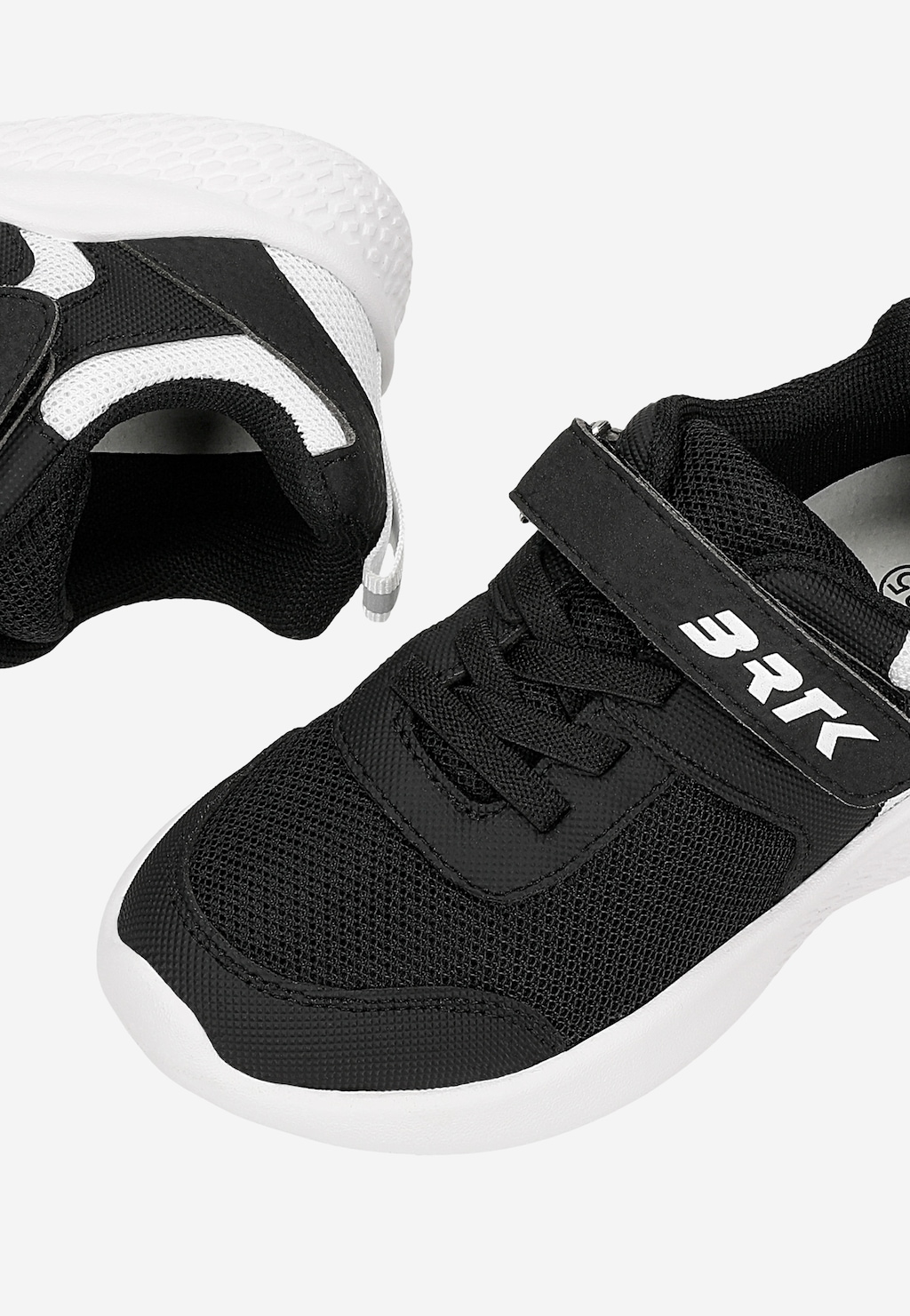 Czarne sneakersy dziecięce Bartek 87003-10 z białymi wstawkami, białą podeszwą i zapięciem na rzep z logo BRTK, widok pary z góry i z boku.