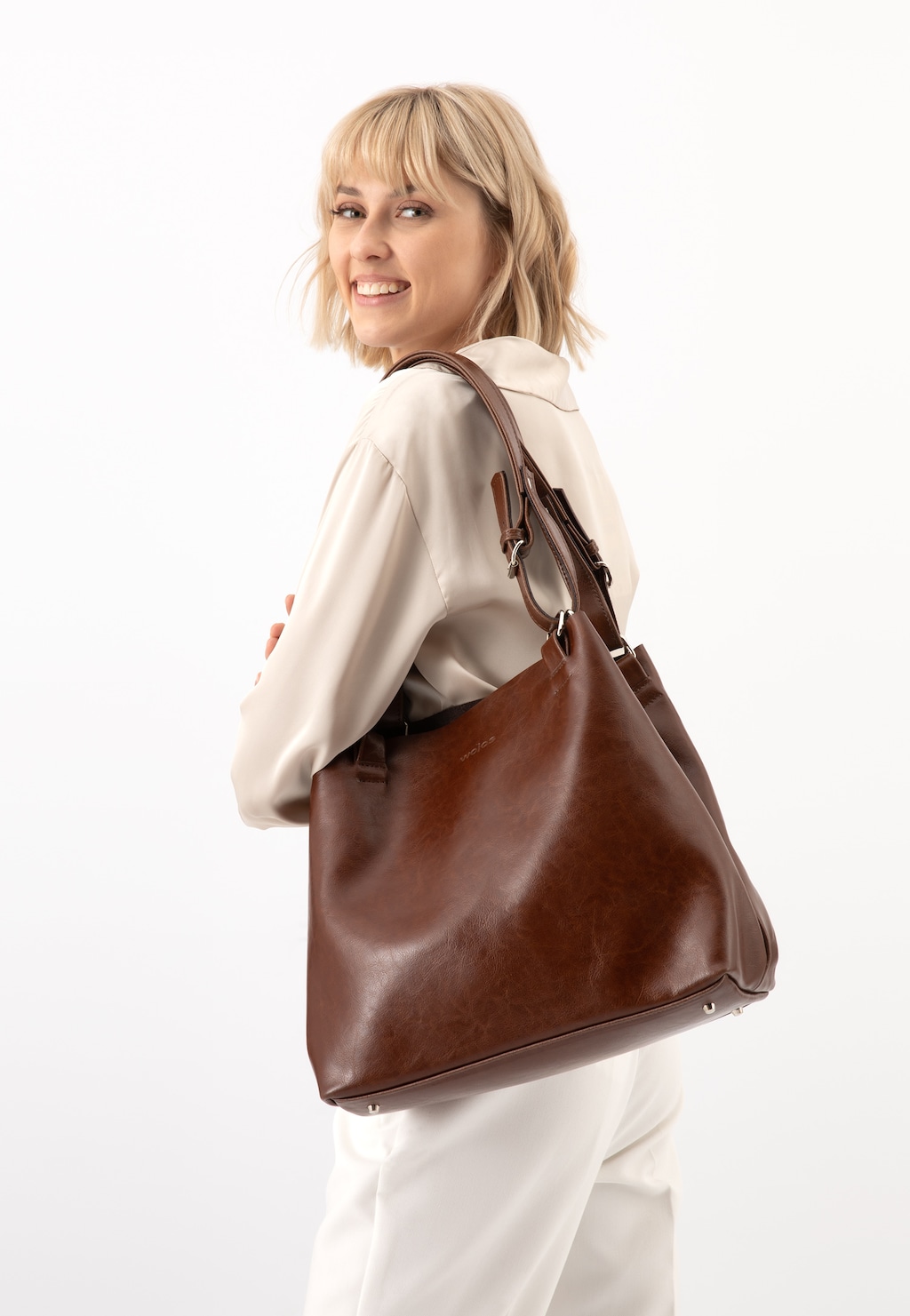 Kobieta z pojemną skórzaną torebką damską Wojas 80246-52 w kolorze brązowym na ramieniu, elegancki styl casual.