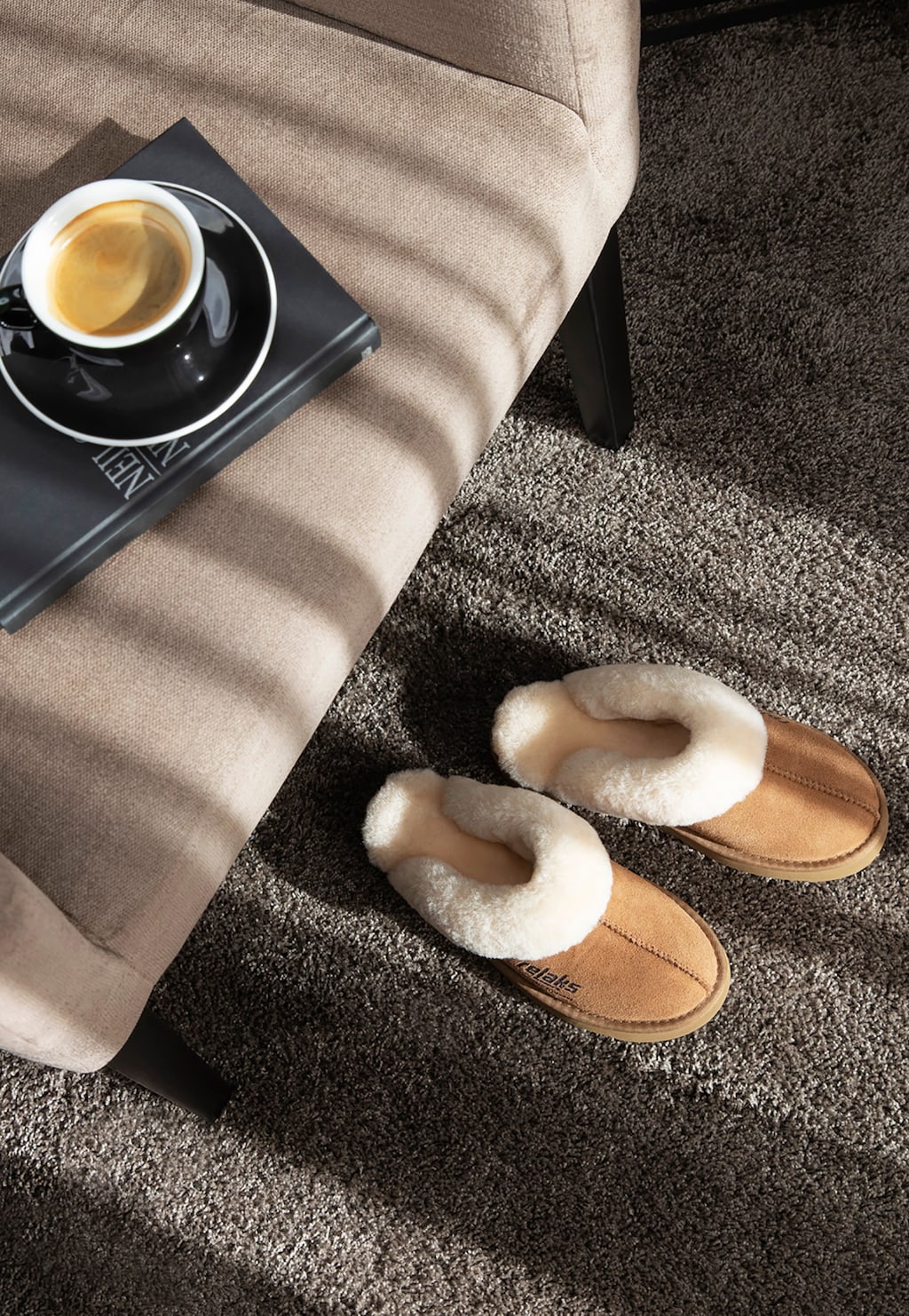 Kapcie Relaks R34001-64 jasnobrązowe z wełną merino na dywanie obok kanapy z kawą i książką