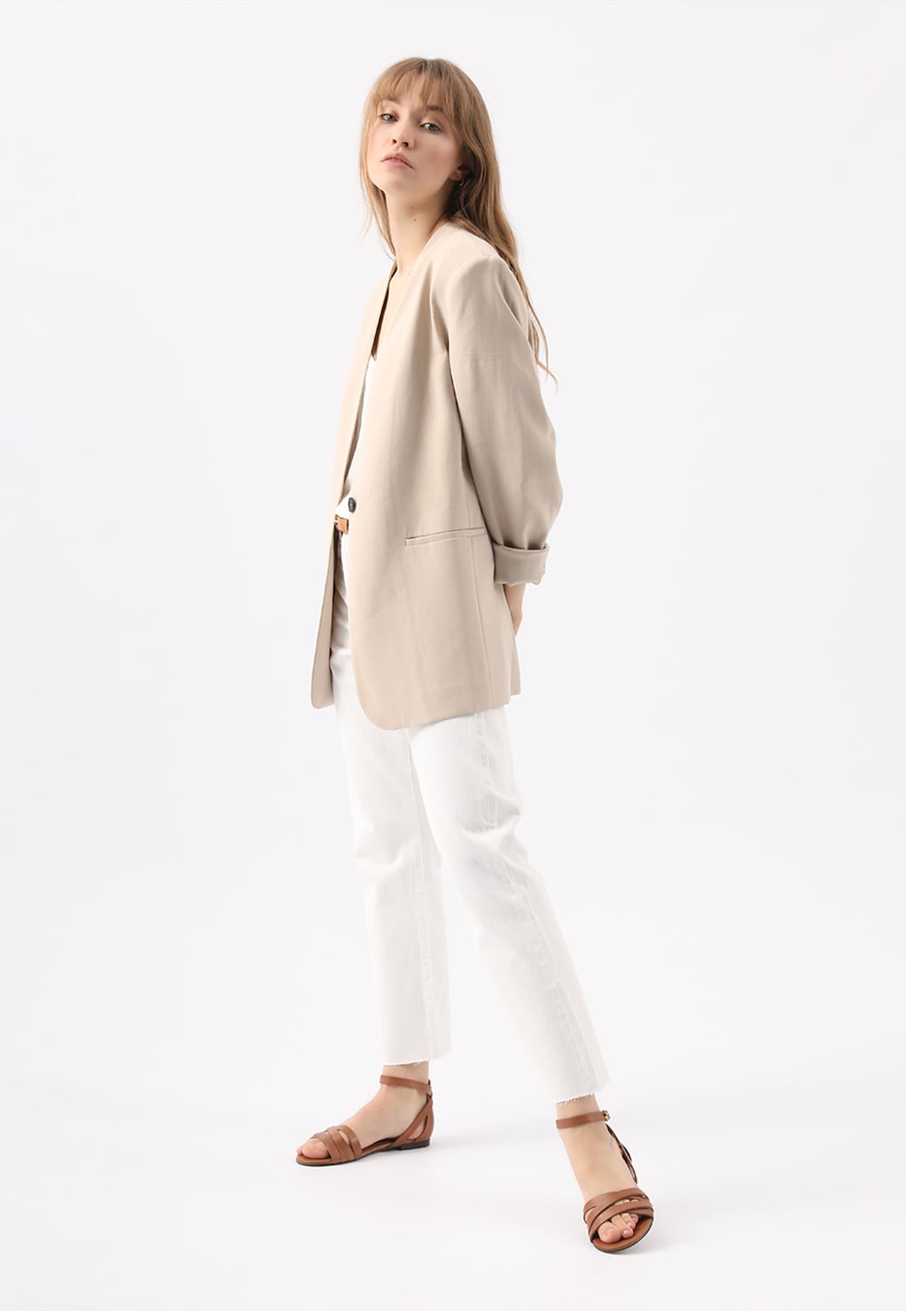 Modelka w beżowym żakiecie i białych spodniach prezentuje brązowe sandały damskie Wojas 76015-53 w stylu urban, ukazane z bocznej perspektywy.