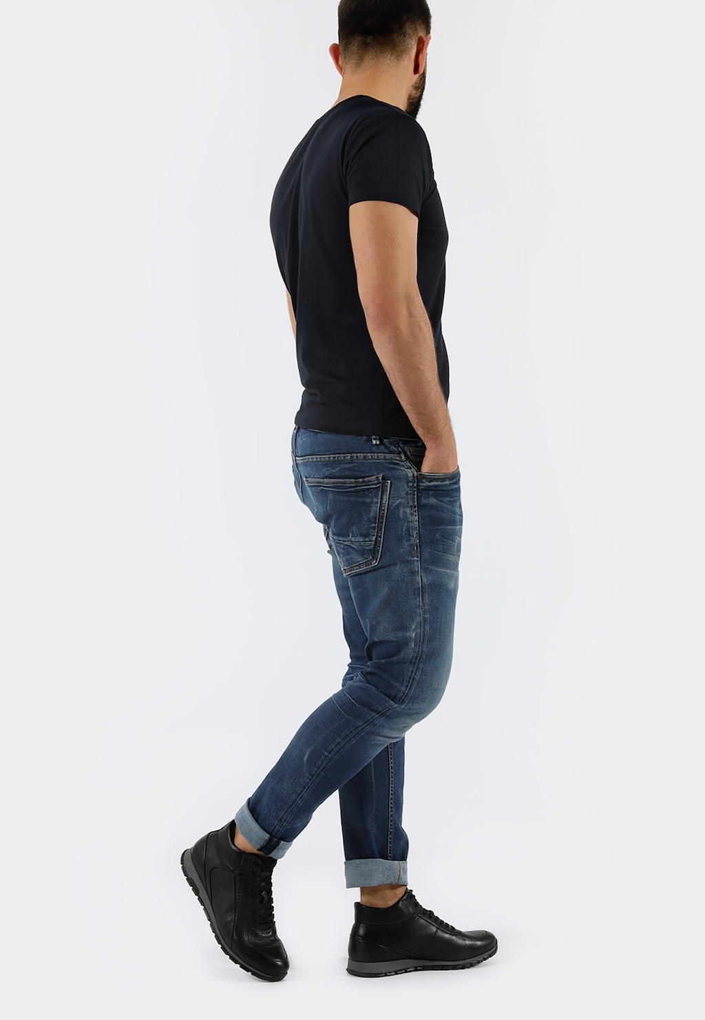 Mężczyzna w czarnej koszulce i jeansach, prezentujący czarne trzewiki męskie Wojas model 9166-51, widok z boku pokazujący stylową sylwetkę obuwia.