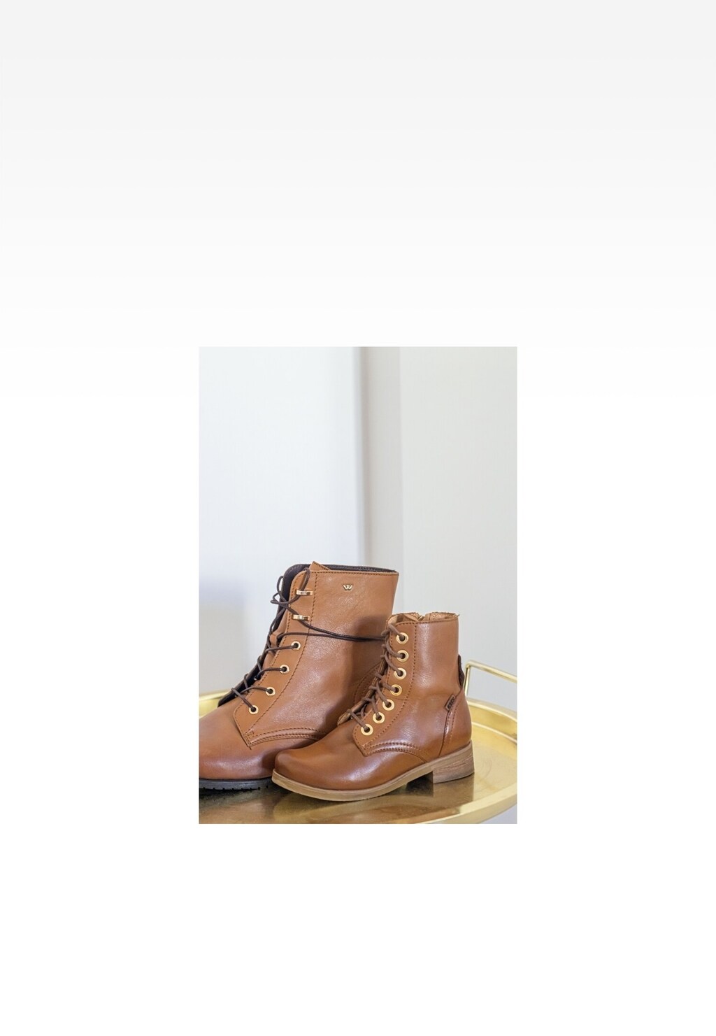 Brązowe trzewiki dziewczęce Wojas x Bartek 8400453 ze skórzaną cholewką i sznurowaniem, ustawione na złotej tacy. Buty z ozdobnymi metalowymi oczkami i niskim obcasem.