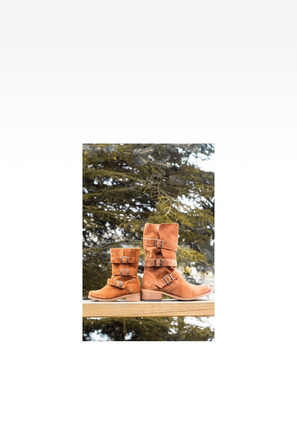 Brązowe botki dziewczęce Wojas x Bartek 8440263 z zamszową cholewką i ozdobnymi klamrami, ustawione na drewnianym podłożu na tle zielonych drzew.