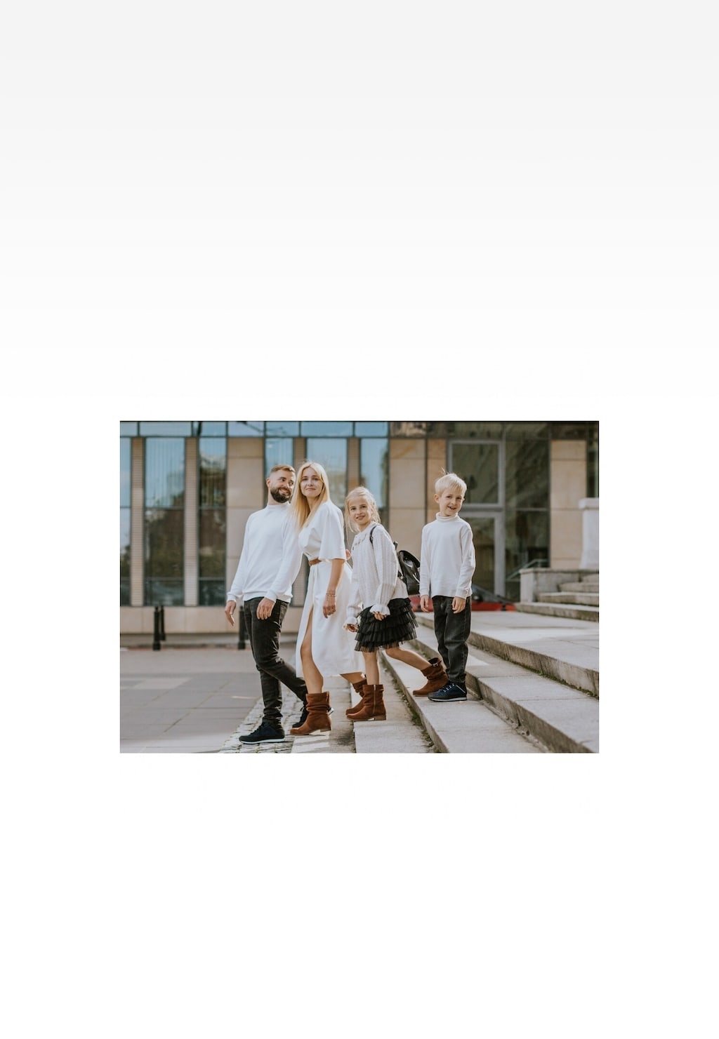 Rodzina w białych strojach przed budynkiem, dziewczynka nosi brązowe botki Wojas x Bartek 8440363, idealne dla młodych fashionistek.
