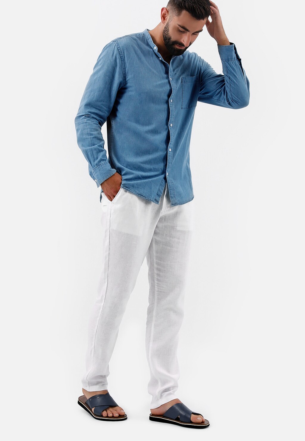 Mężczyzna w niebieskiej koszuli i białych spodniach prezentujący granatowe klapki Wojas model 9259-56 wykonane ze skóry licowej, idealne do letnich stylizacji.