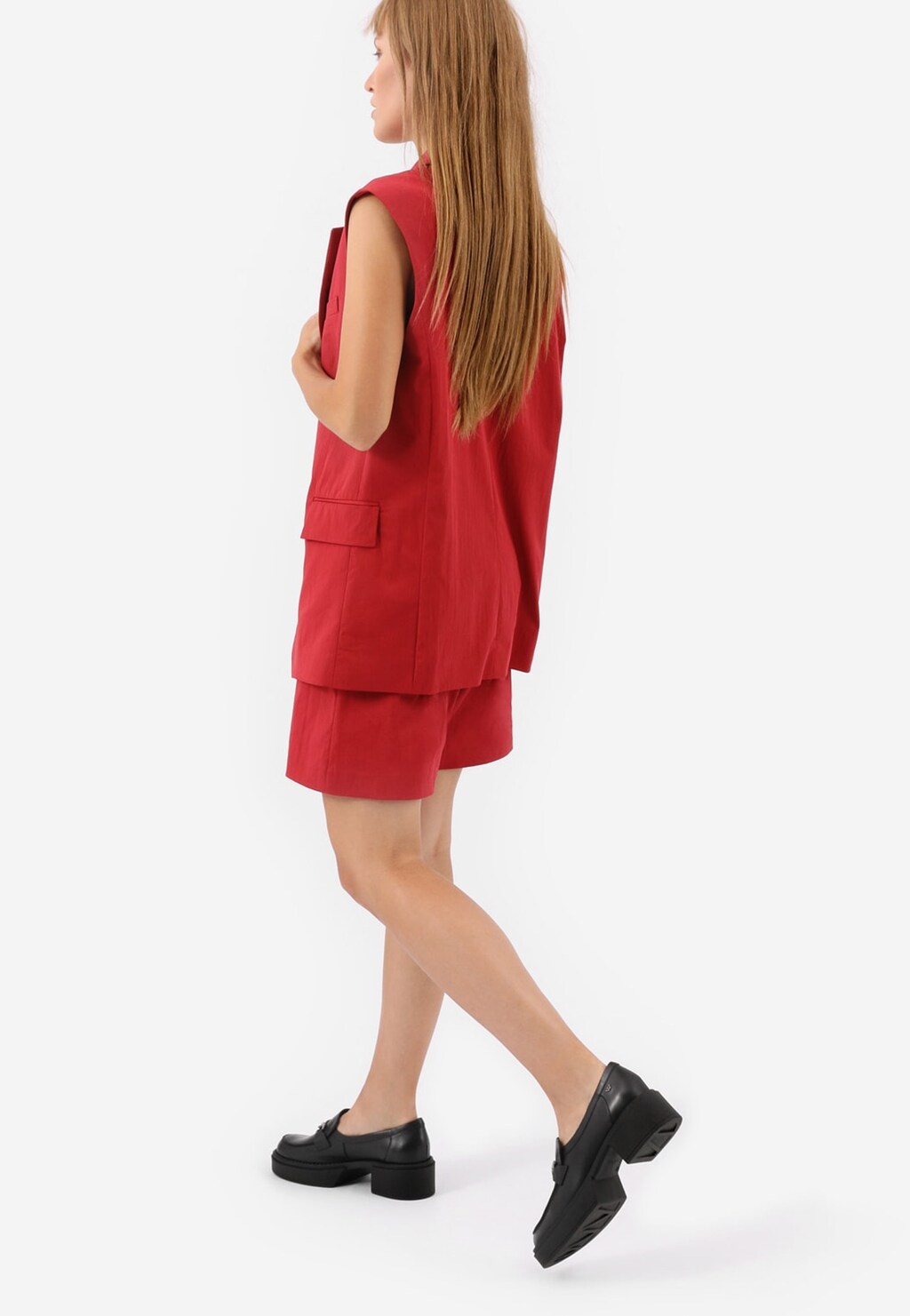 Kobieta w czerwonym komplecie z kamizelką i szortami, nosząca czarne mokasyny damskie Wojas model 46113-51 w stylu urban, widok z profilu.