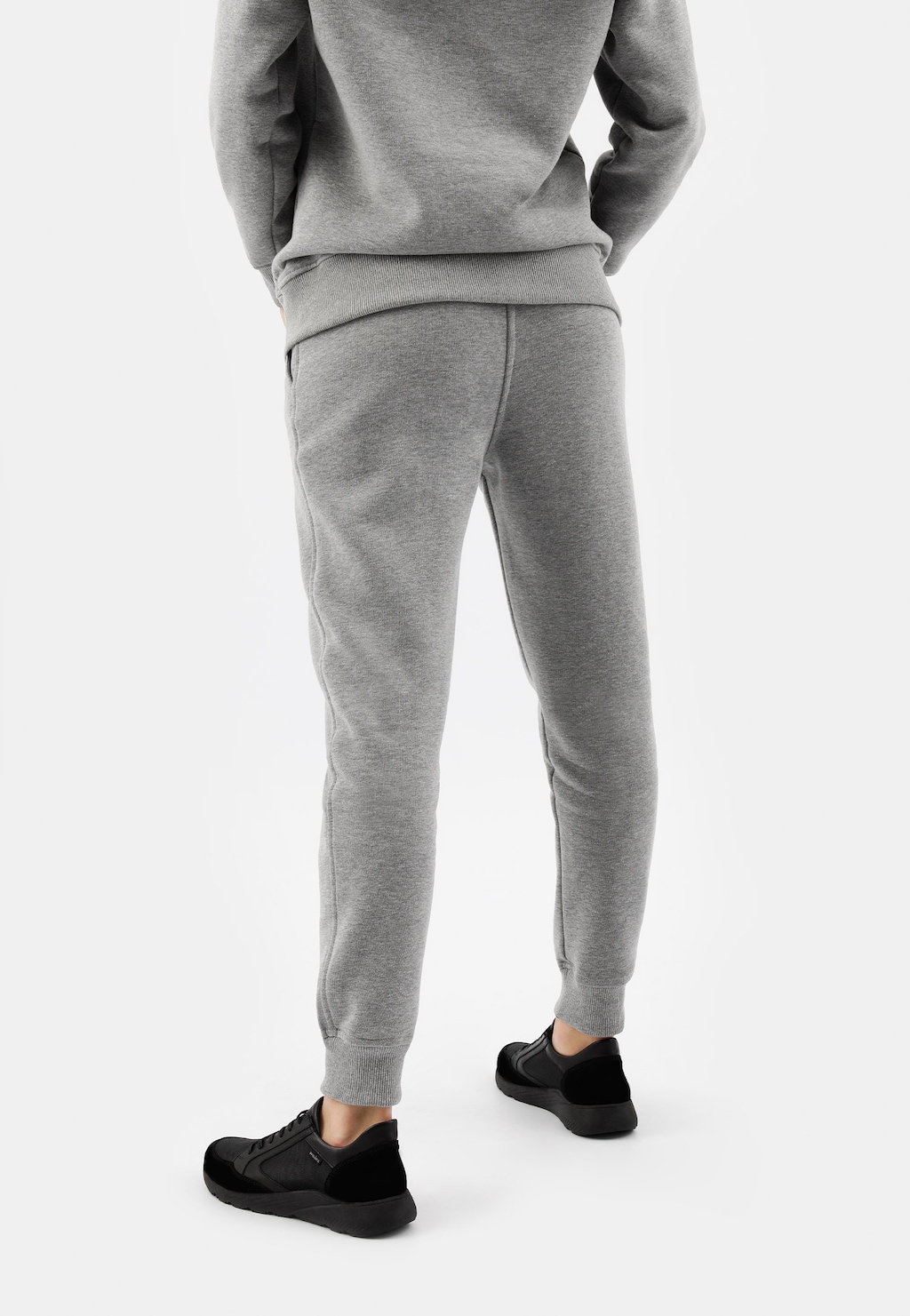 Popielate spodnie dresowe damskie Relaks 98024-80 z bawełny, widok z tyłu ukazujący dopasowany krój i elastyczny pas, noszone z czarnymi butami sportowymi.