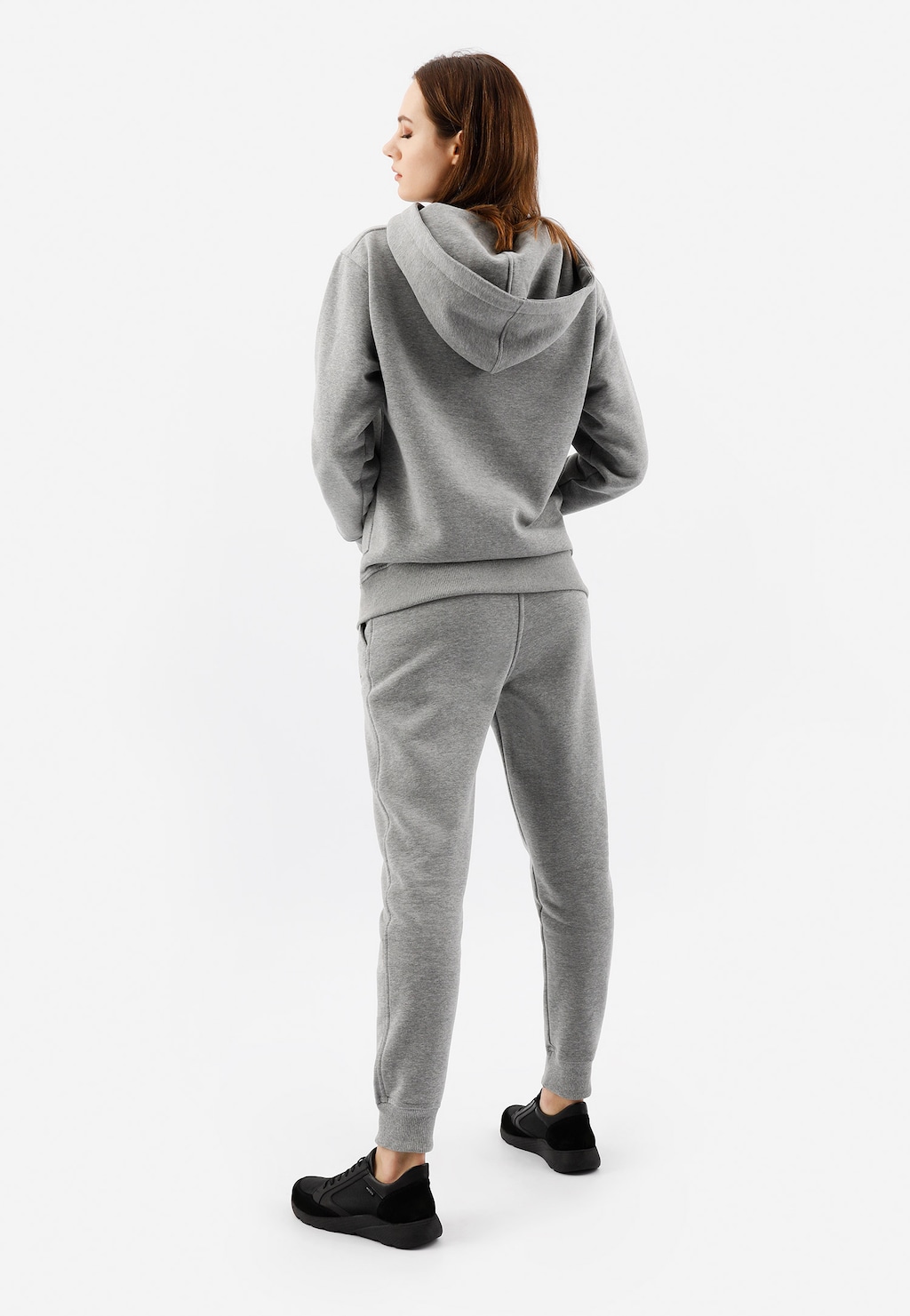 Popielate spodnie dresowe damskie bawełniane model 98024-80 Relaks prezentowane z tyłu na modelce, w komplecie z bluzą z kapturem, tworzące wygodny zestaw sportowy.