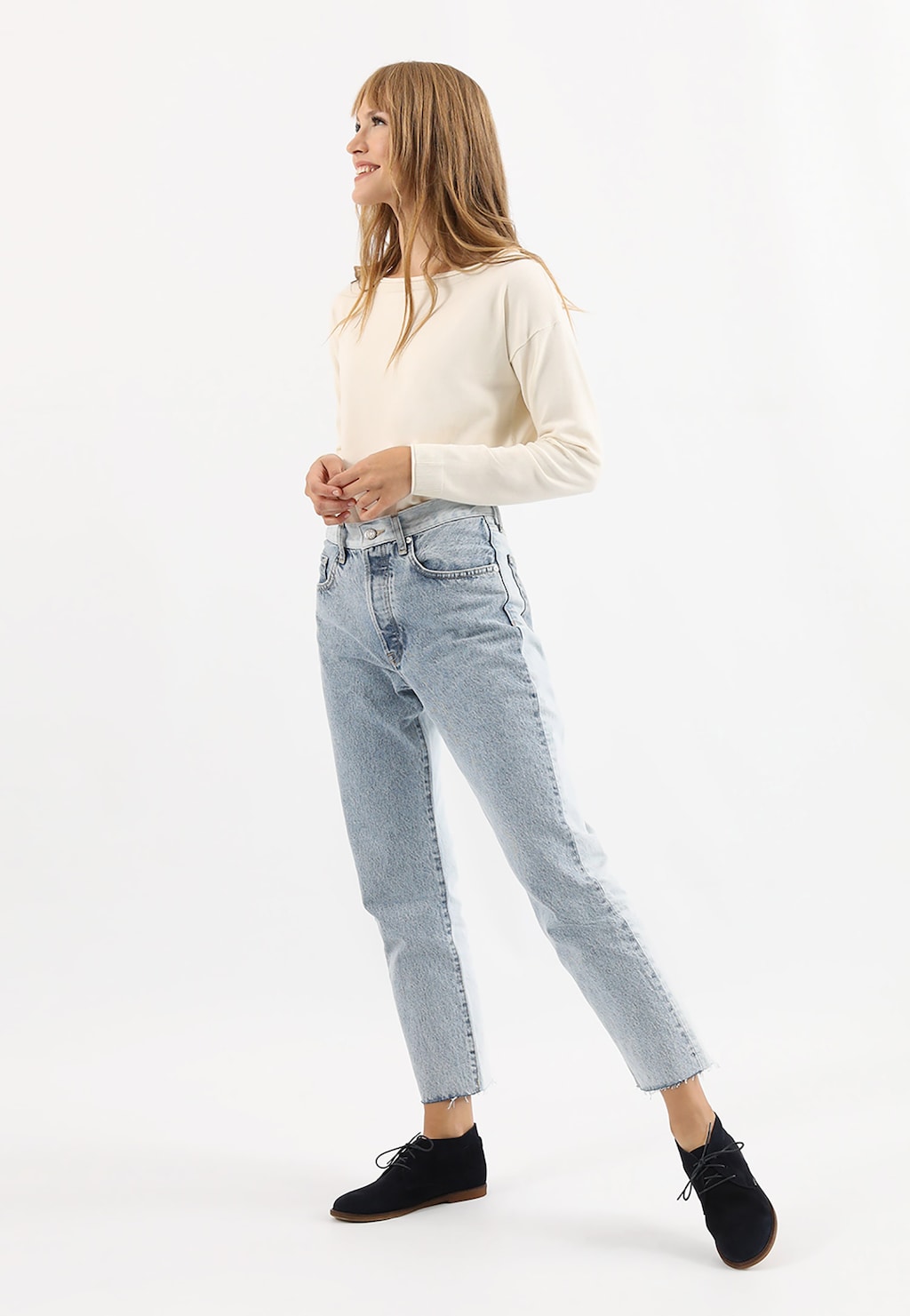 Kobieta w kremowym swetrze i jasnoniebieskich jeansach, prezentująca granatowe skórzane trzewiki damskie Wojas model 64066-66, widoczne na nogach jako eleganckie czarne buty.